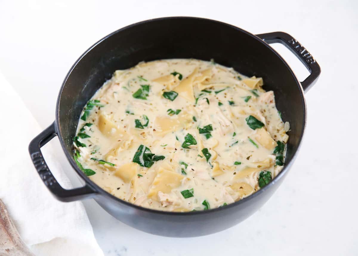 Rich and hearty creamy white lasagna soup is packed with tender shredded chicken, lasagna noodles, Italian spices, spinach, and a velvety broth with cream and Parmesan cheese. It's a comforting version of the classic pasta dish but without the hassle of layering the noodles! White lasagna soup in a black pot.