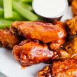 Baked chicken wings on a plate with celery.