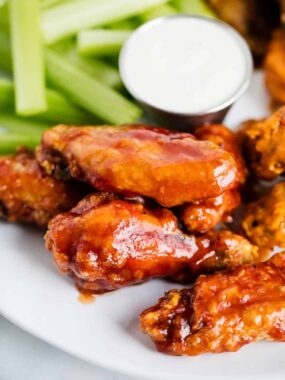 Baked chicken wings on a plate with celery.