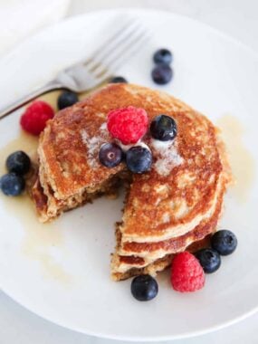 Stack of oatmeal blender pancakes served with berries and maple syrup.