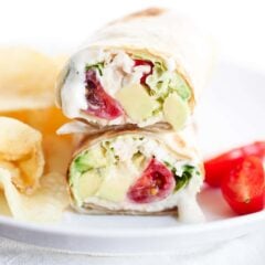 Chicken caesar wrap with chips on a white plate.