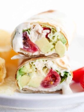 Chicken caesar wrap with chips on a white plate.