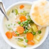 Chicken pot pie soup in a bowl with biscuit.