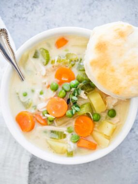 Chicken pot pie soup in a bowl with biscuit.