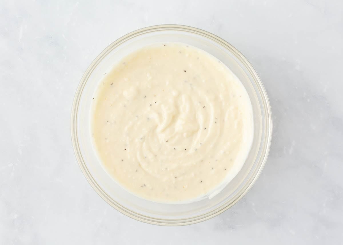 Creamy 7 layer salad dressing made with mayo, Parmesan and seasonings whisked together in a glass bowl.