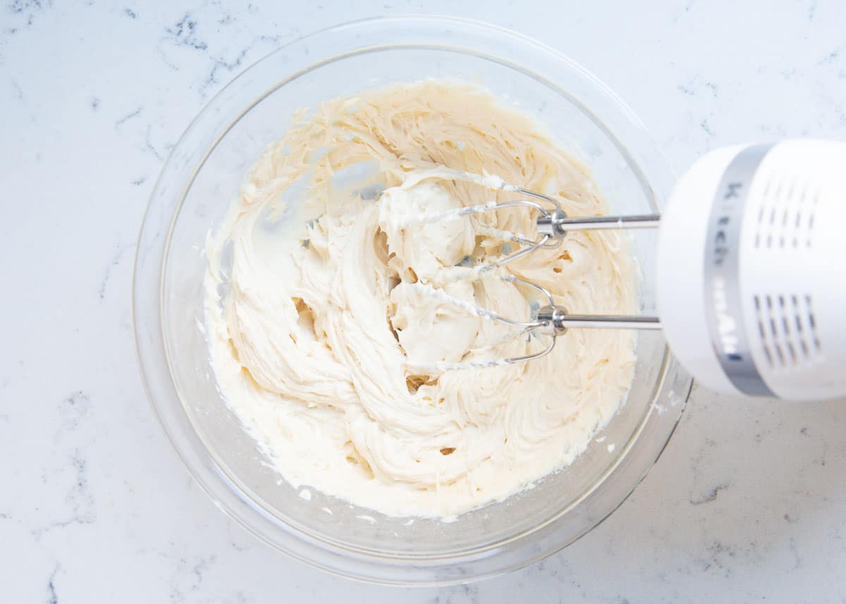 Mixing cheesecake dip in glass bowl.