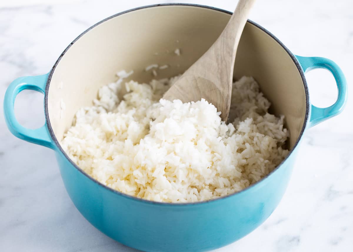 Rice in a blue saucepan with a wooden spoon. 