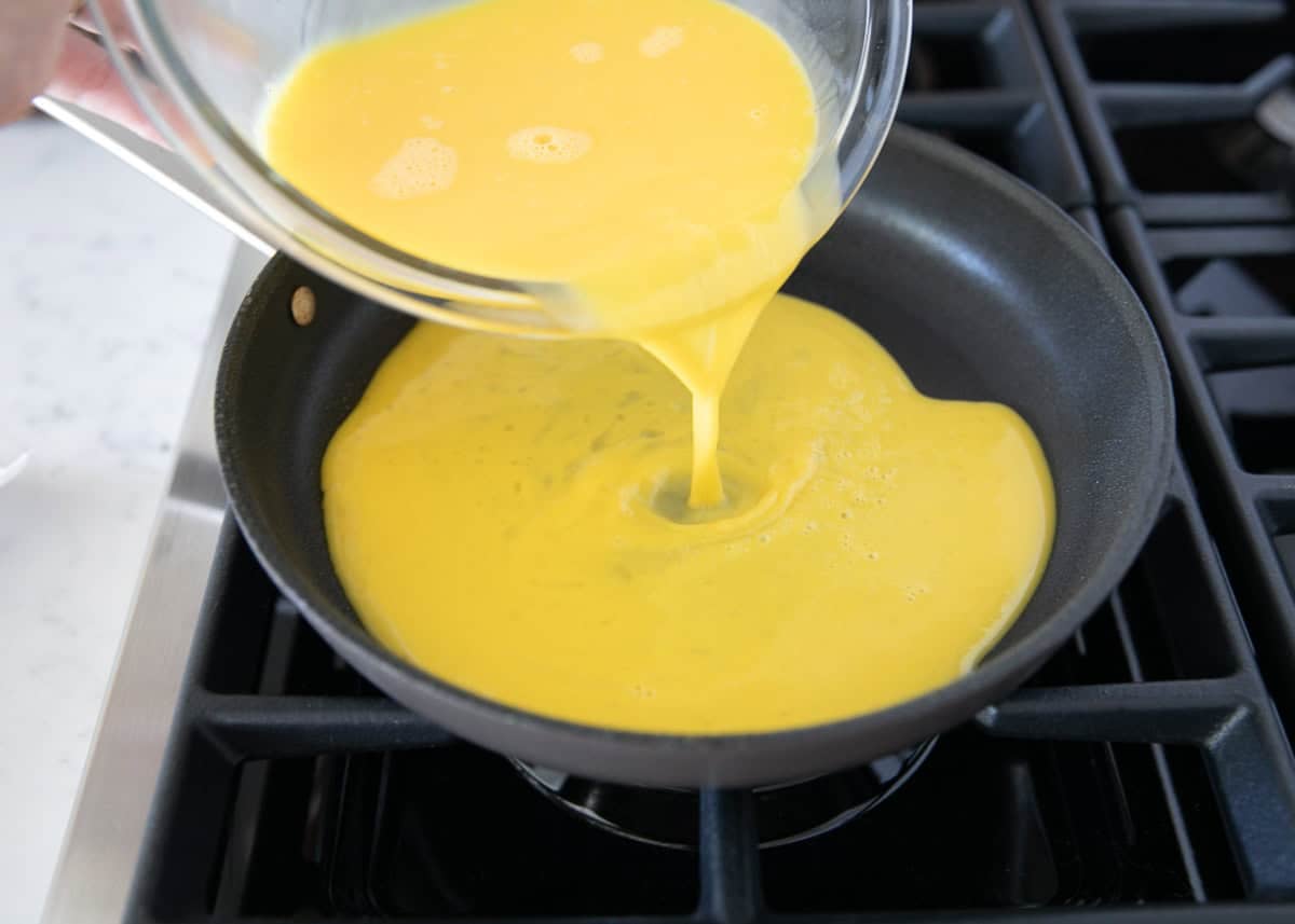 Pouring whisked eggs into a buttered nonstick skillet.