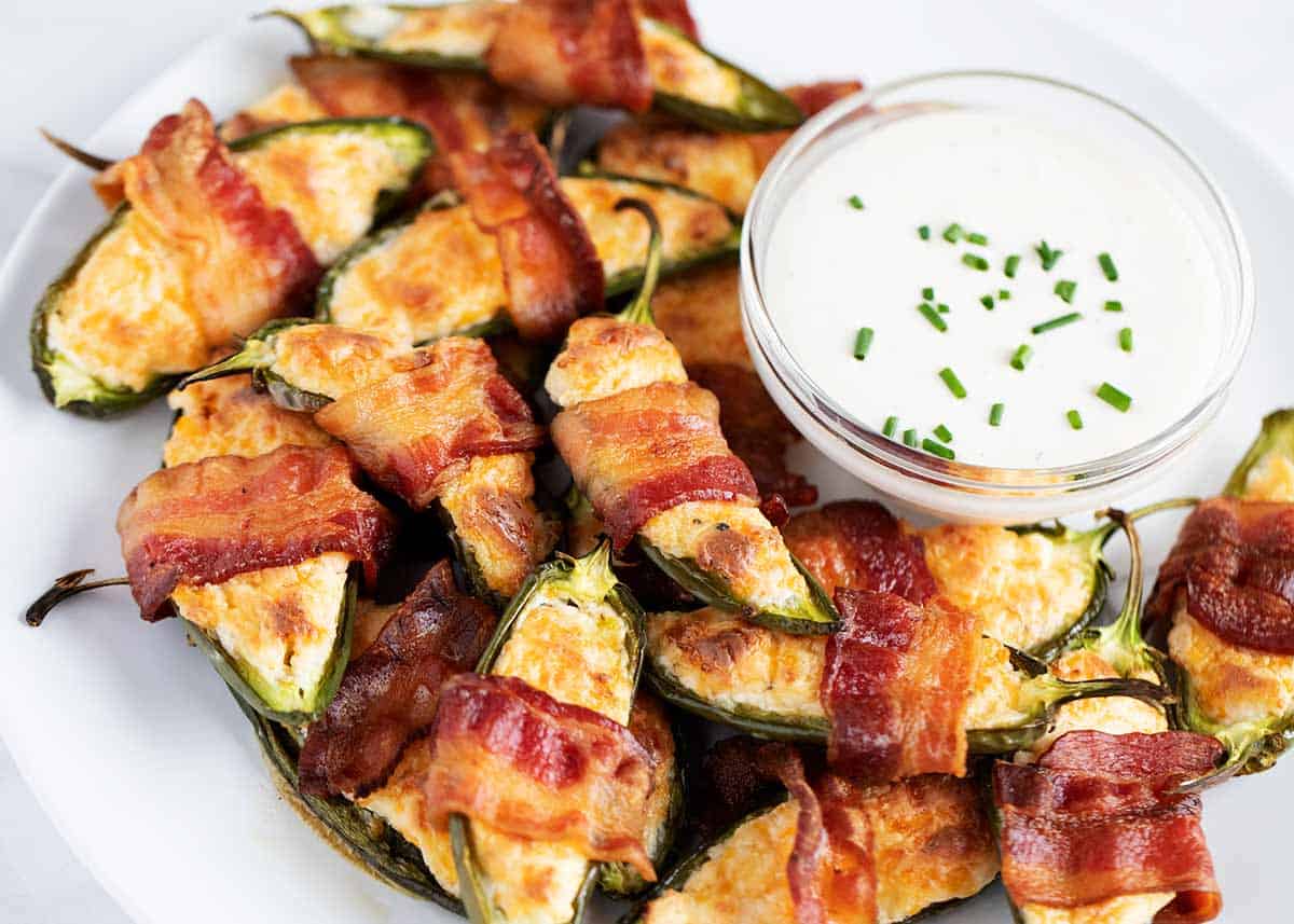 Jalapeno poppers on a white plate with ranch on the side. 