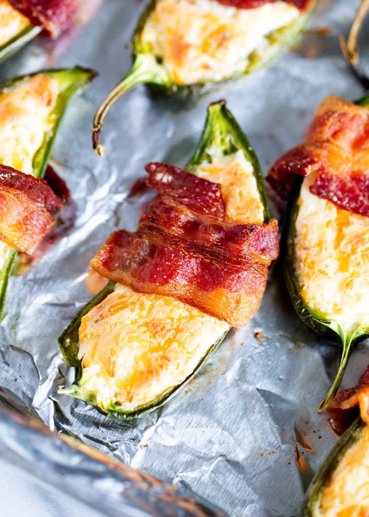 Bacon wrapped jalapeno poppers on a baking sheet. 