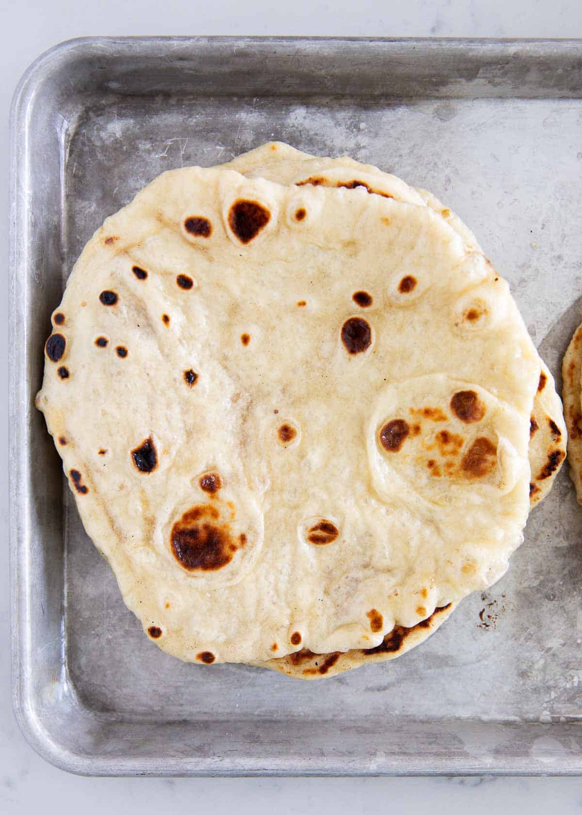 Naan bread on baking sheet.