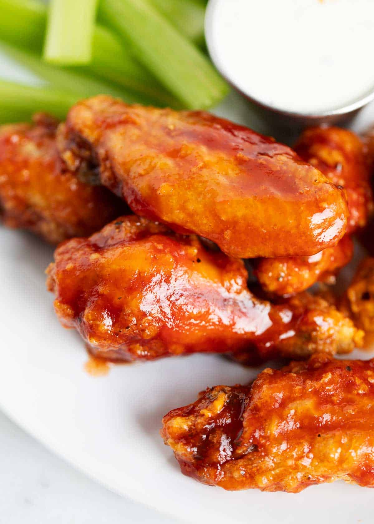 Chicken wings on a plate with celery with ranch.