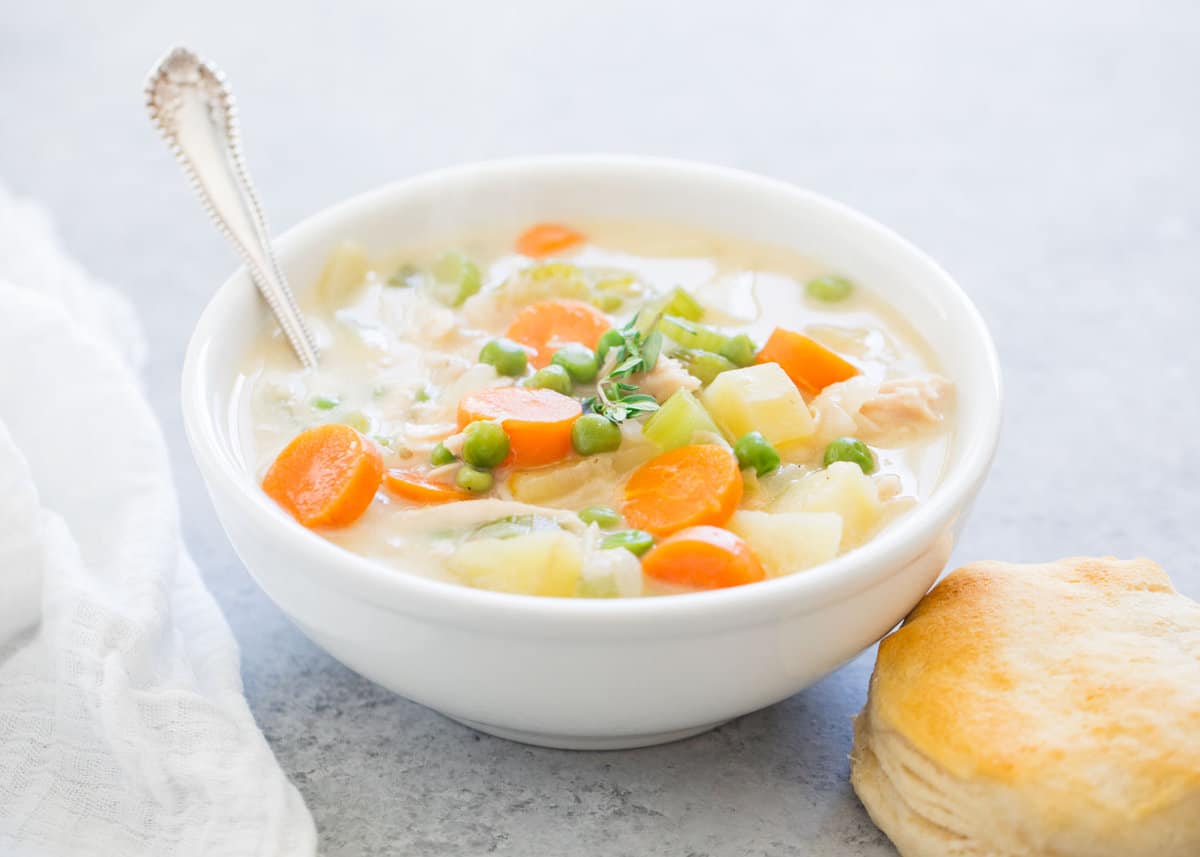 Chicken pot pie soup in a bowl with a biscuit.