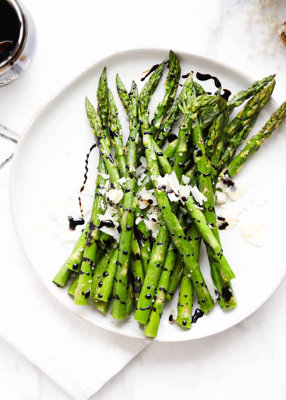 Roasted asparagus on a white plate garnished with balsamic. 