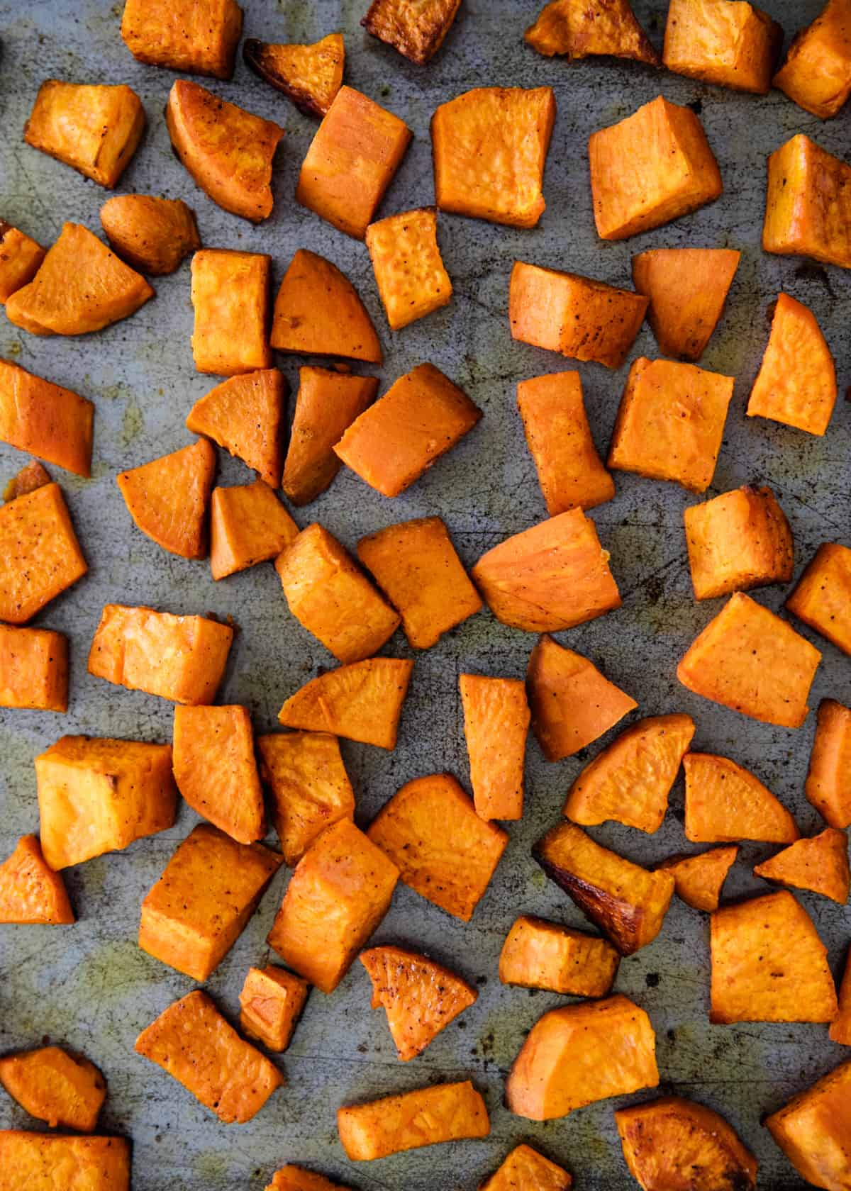 Roasted sweet potatoes on a sheet pan.