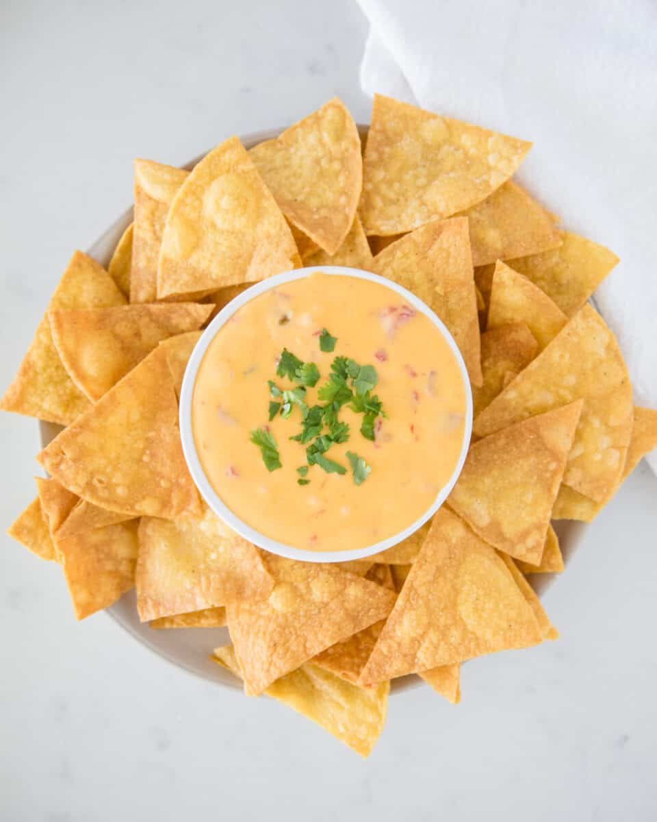 A bowl full of queso cheese with tortilla chips.