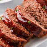 Sliced bbq meatloaf on white plate.