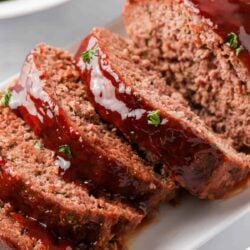 Sliced bbq meatloaf on white plate.