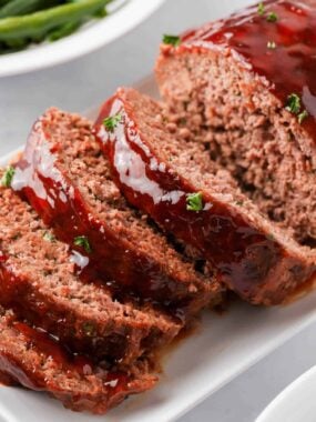 Sliced bbq meatloaf on white plate.