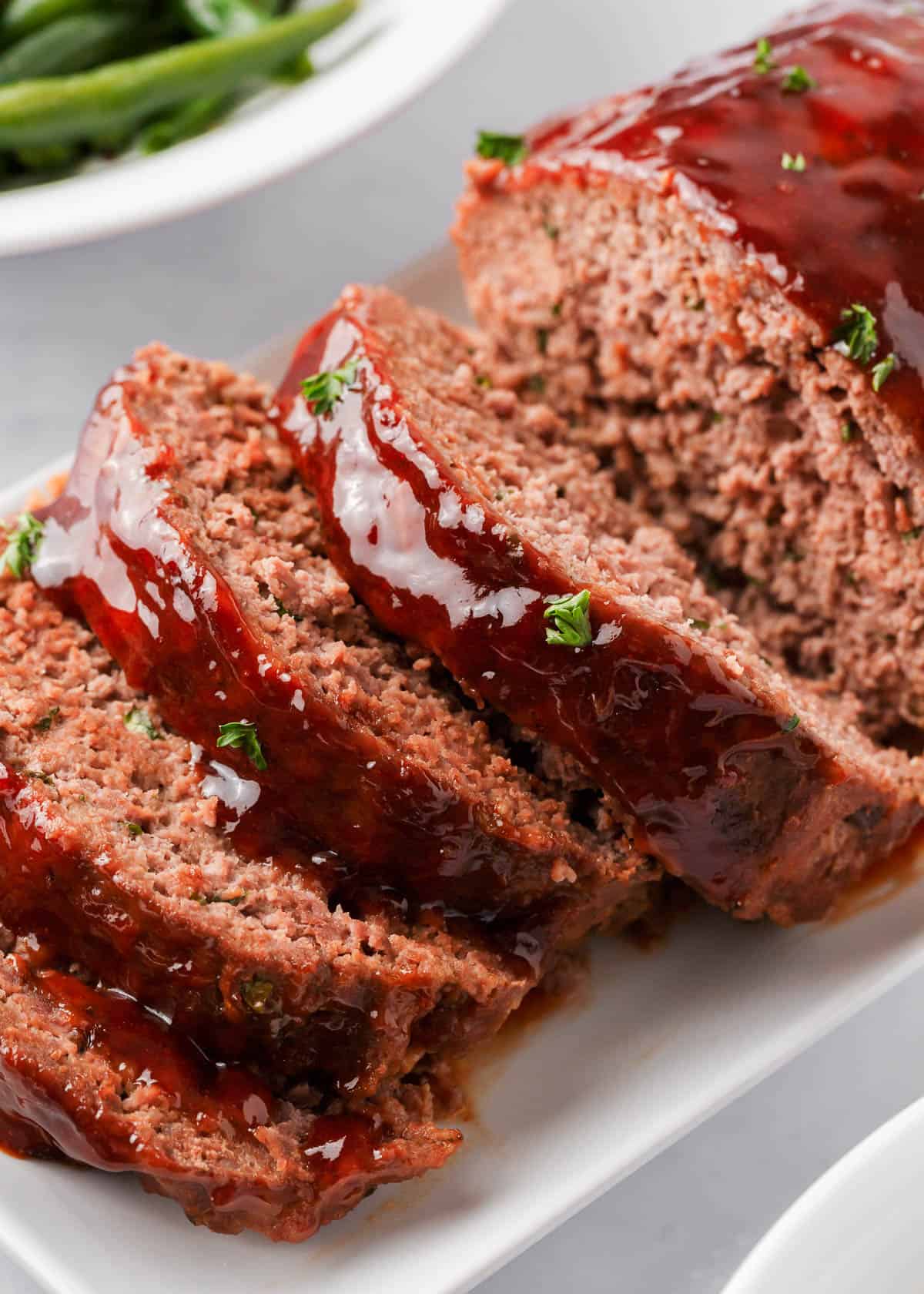 Sliced bbq meatloaf on white plate.