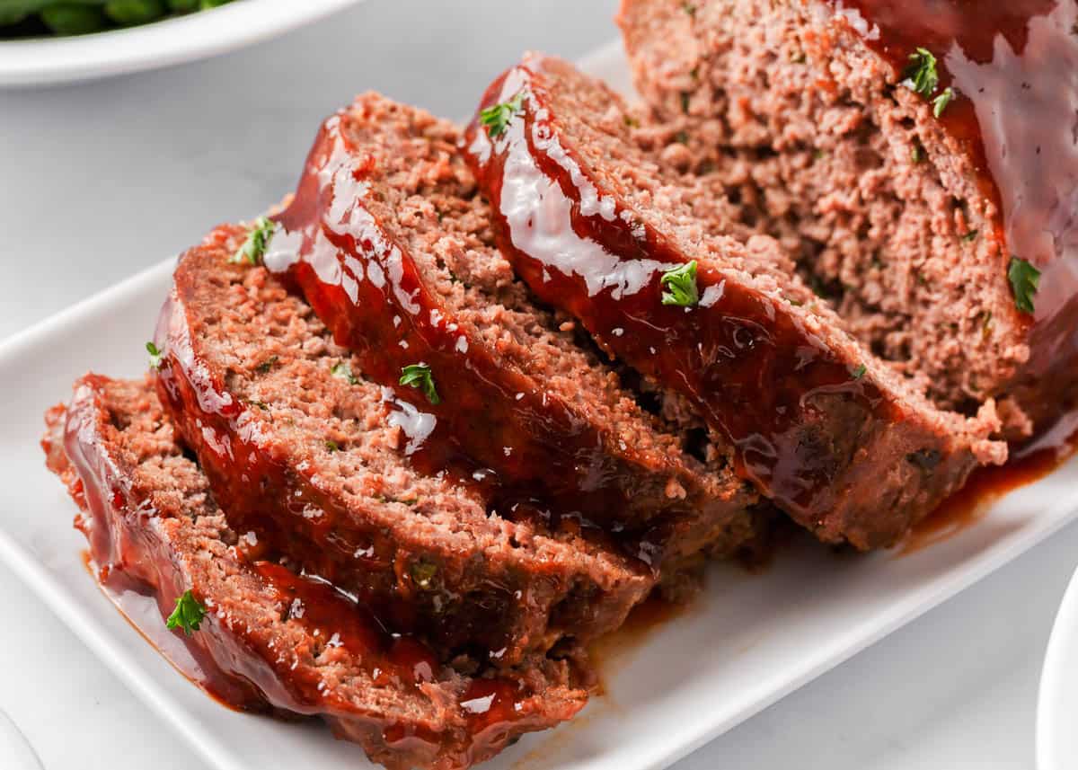 Sliced bbq meatloaf on white plate.