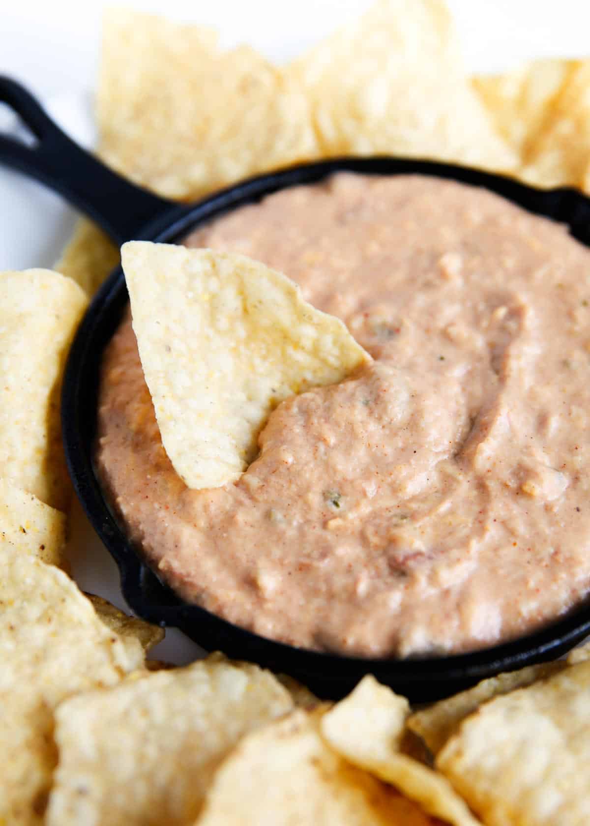 This is the best bean dip with cream cheese recipe! Made with refried beans and 3 kinds of cheese, it's the perfect party dip served warm with tortilla chips. Bean dip and tortilla chips on platter.