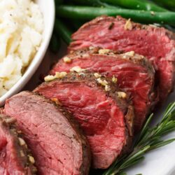 Sliced beef tenderloin on a white plate.