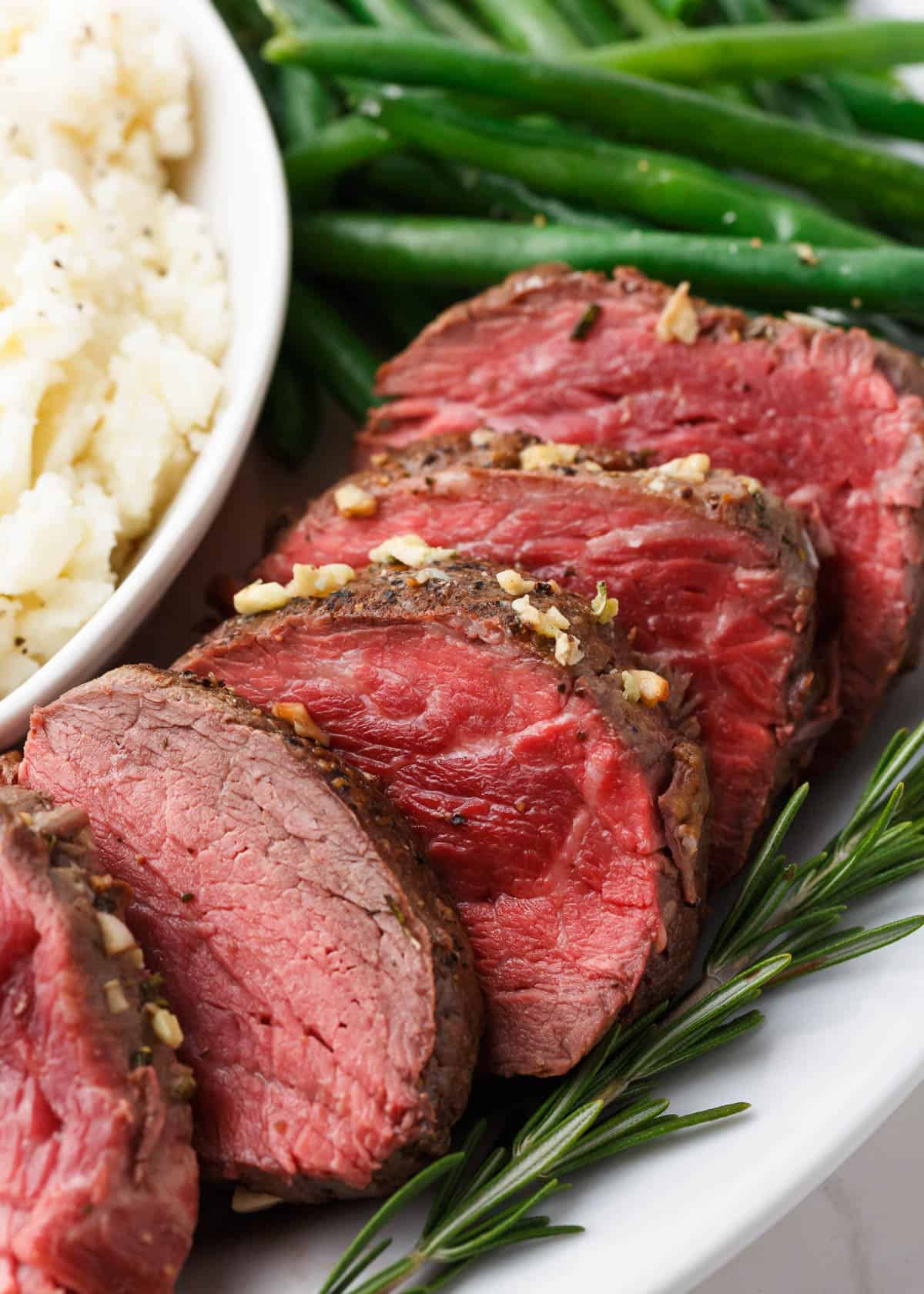 Sliced beef tenderloin on a white plate.