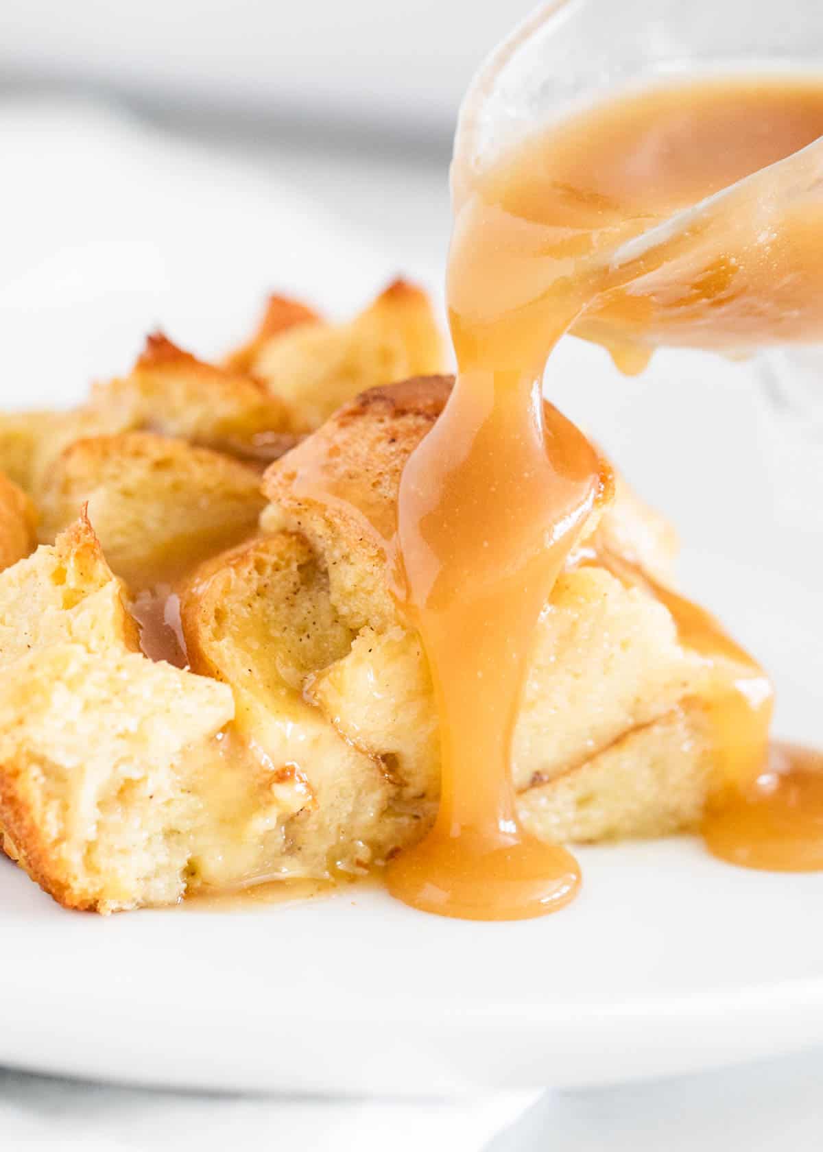 Bread pudding with caramel sauce being poured overtop. 