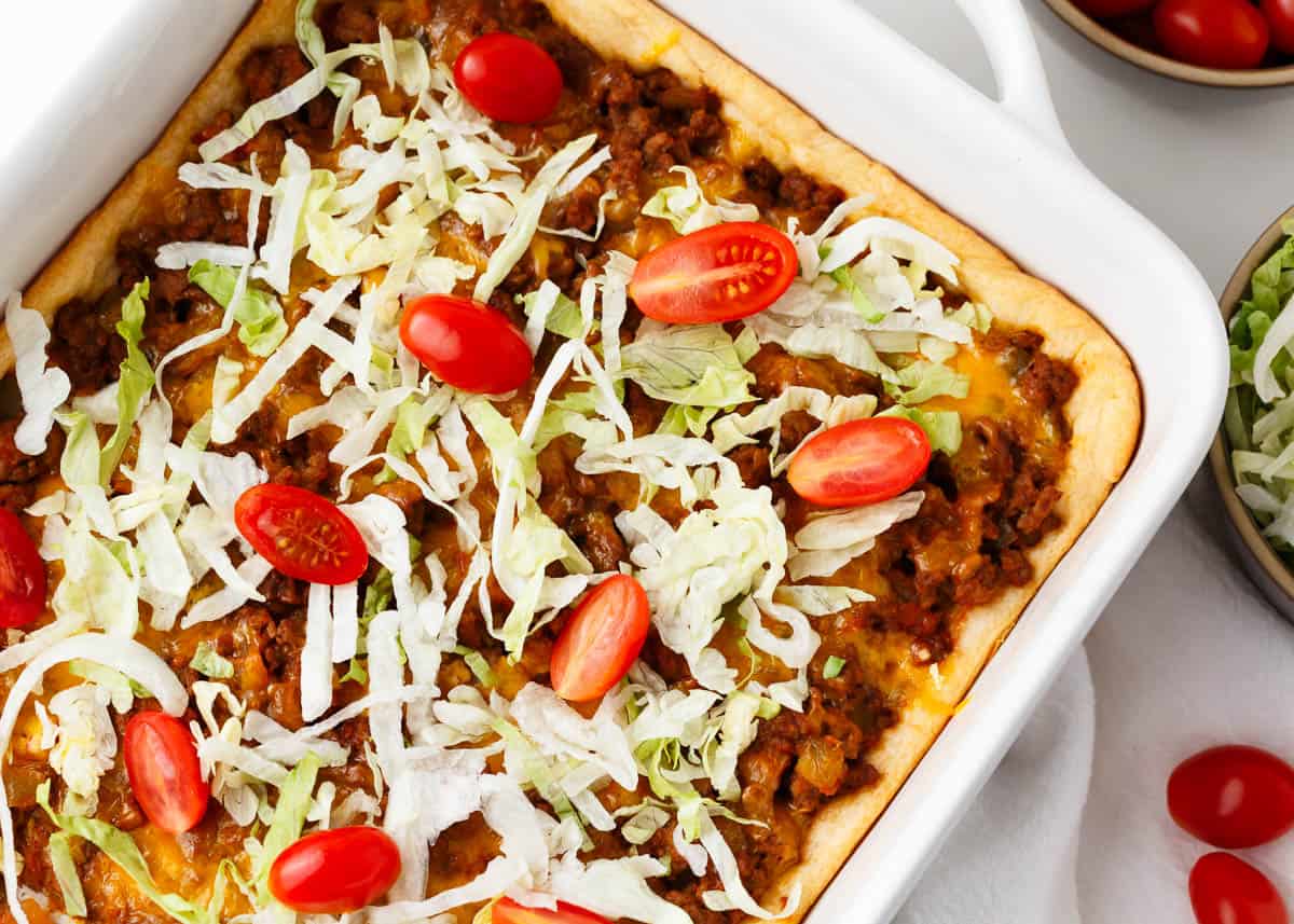 Crescent roll taco bake in a white baking dish.