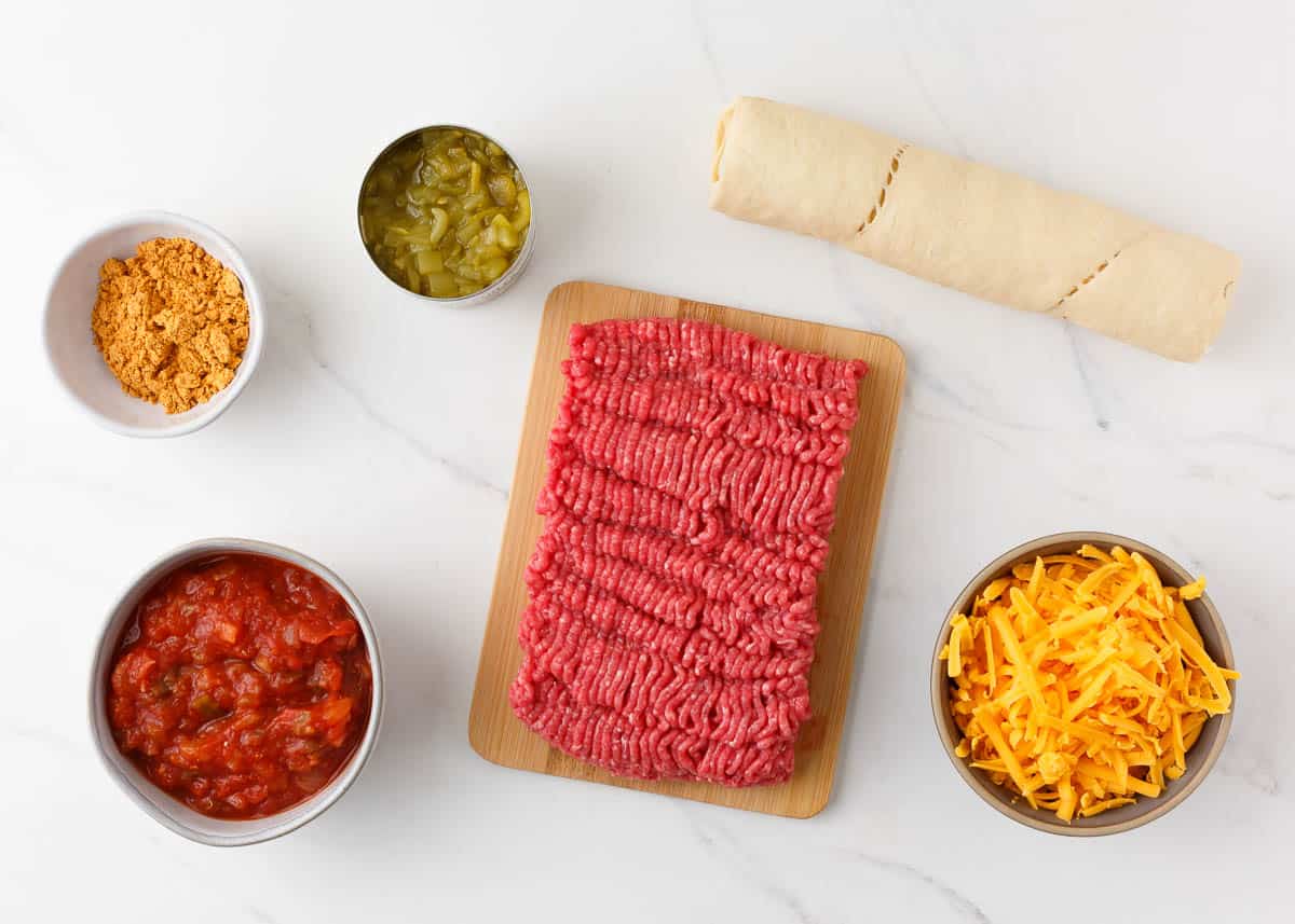 Crescent roll taco bake ingredients on a marble counter.