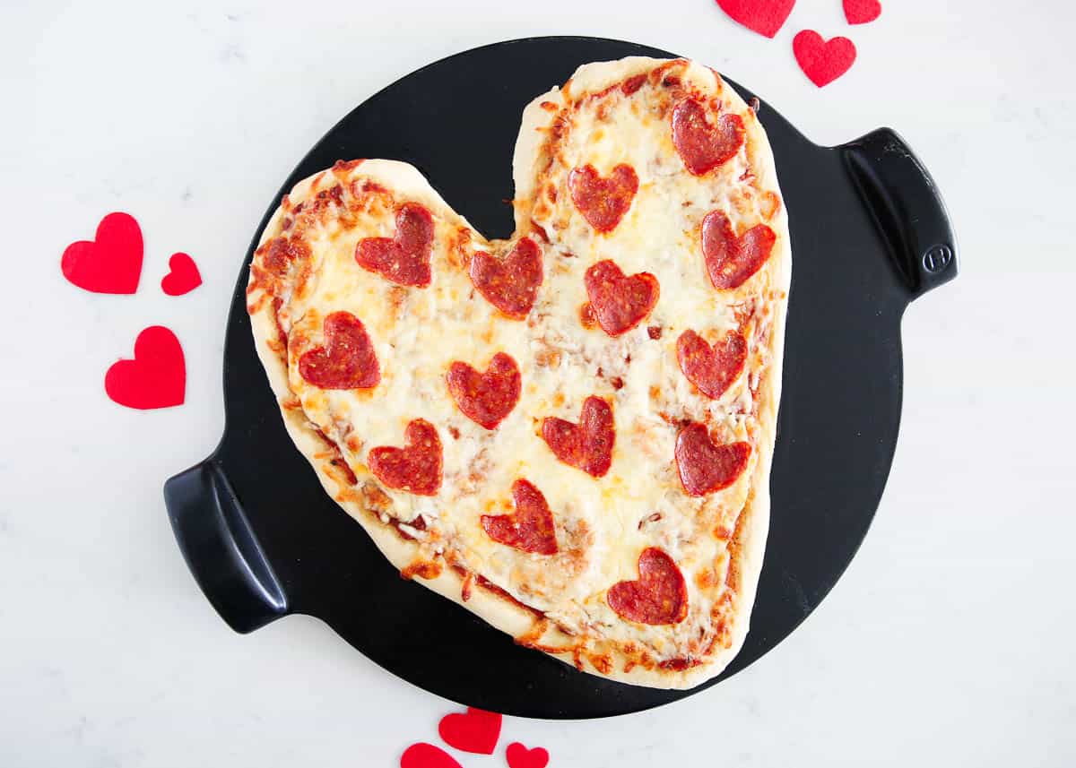 Heart shaped pizza on counter.