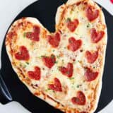 Heart shaped pizza on pizza stone.