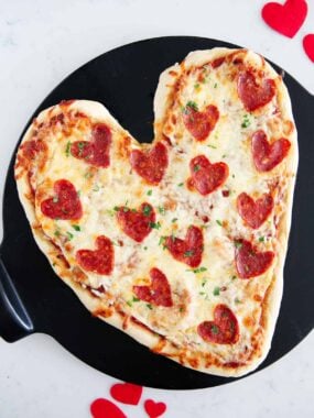 Heart shaped pizza on pizza stone.