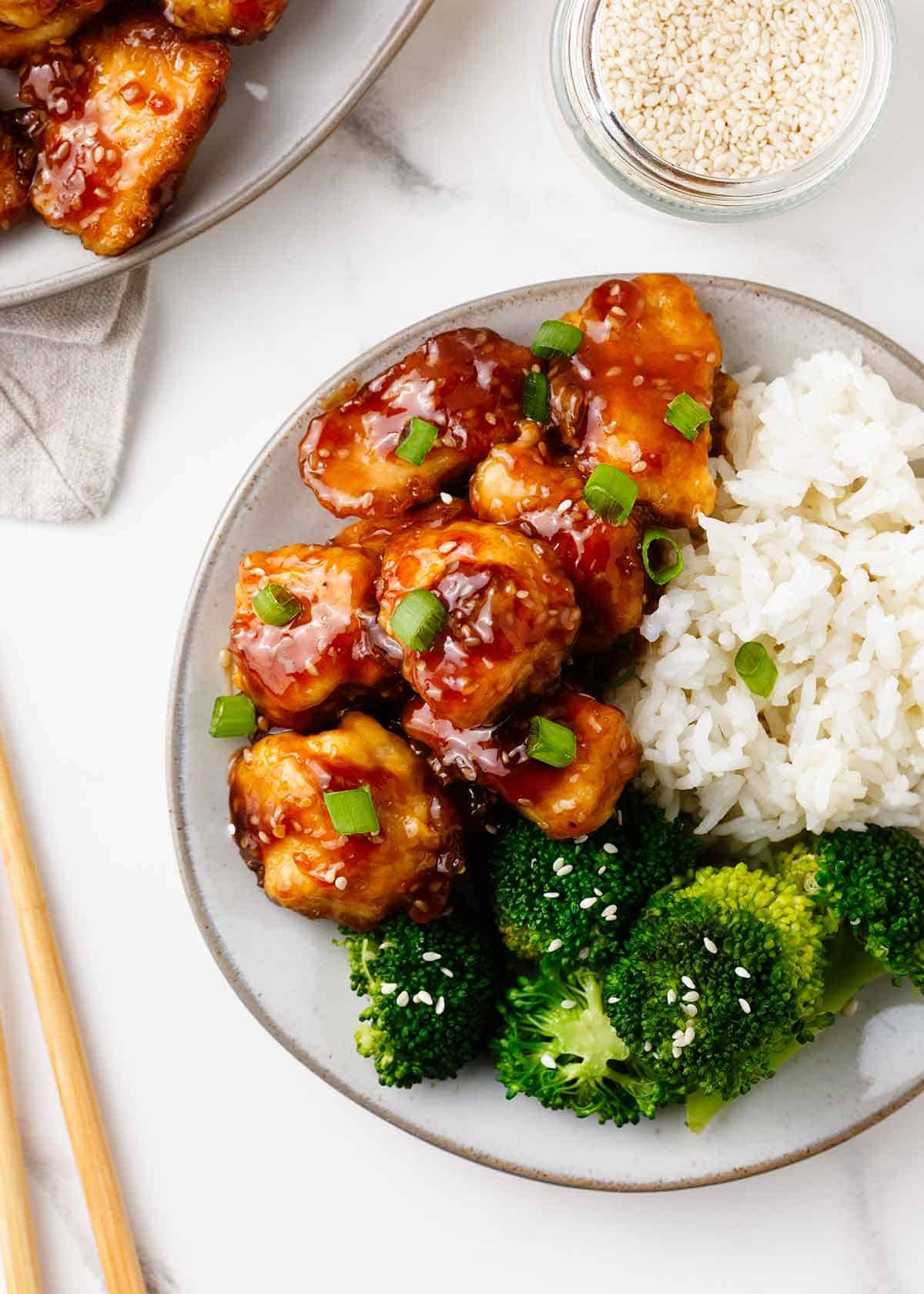 Honey sesame chicken with rice and broccoli on a plate. 