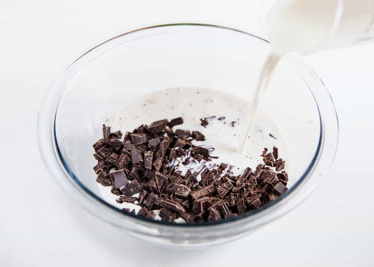 A glass bowl of chocolate and heavy cream. 