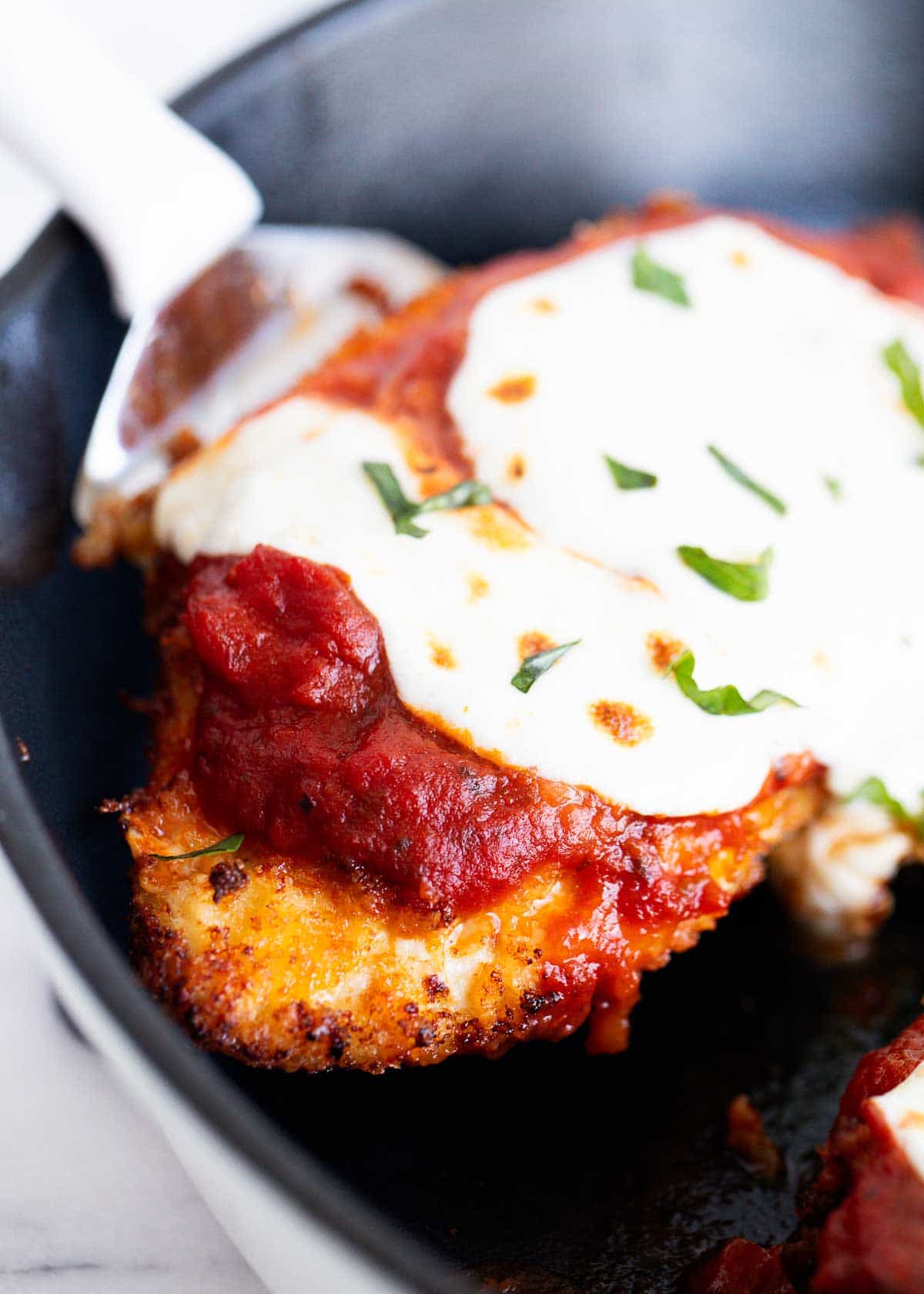 The chicken parmesan cooked in the pan. 