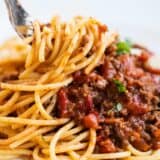 Twisting spaghetti bolognese on fork.