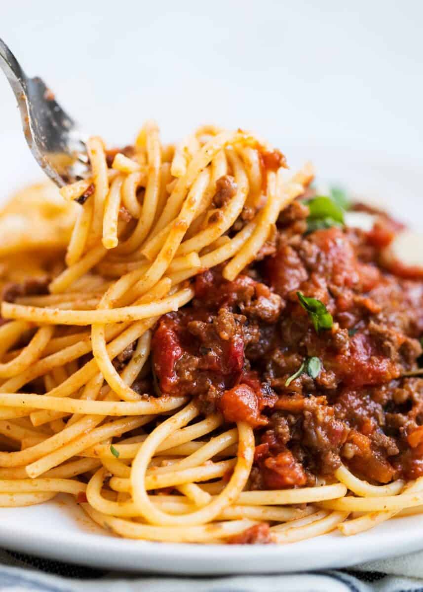 Twisting spaghetti bolognese on fork.