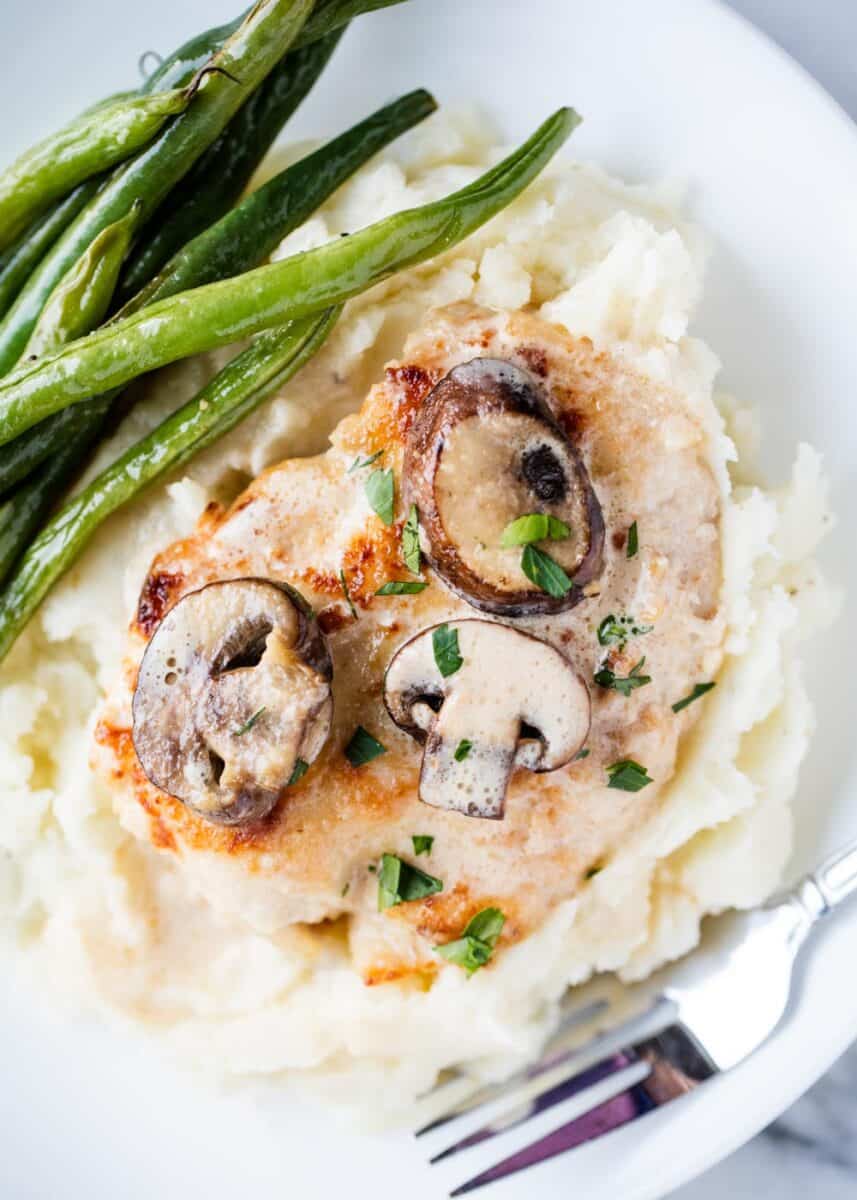 Chicken marsala with mashed potatoes on a white plate.