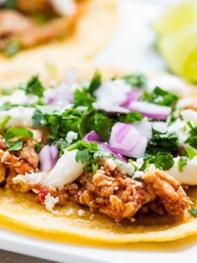 Chicken tinga tacos on a white plate.