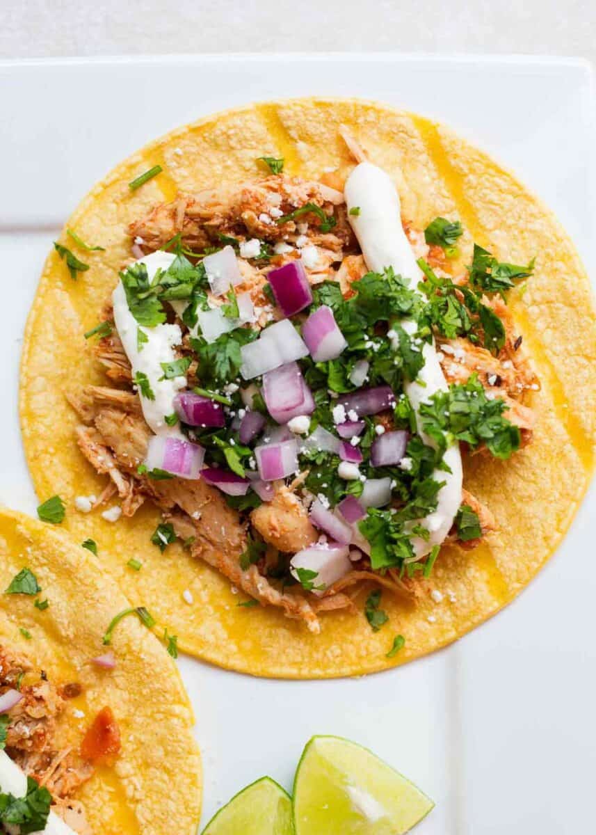 Chicken tinga taco with toppings on a white plate.