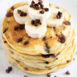 Stack of chocolate chip pancakes with chocolate chips and bananas.