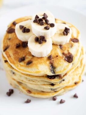 Stack of chocolate chip pancakes with chocolate chips and bananas.
