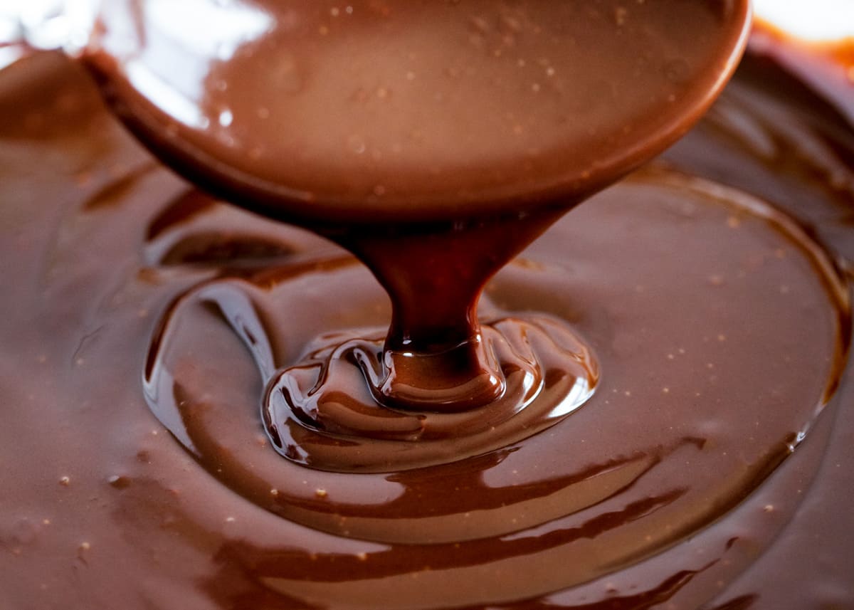 Chocolate ganache is pouring from a spoon. 