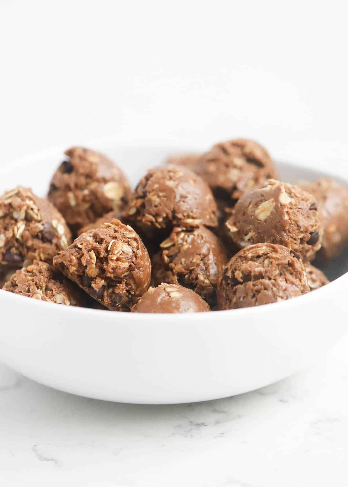 These chocolate peanut butter protein balls taste like no bake cookies but healthier! These make the perfect pre-work out snack, breakfast or dessert! A bowl full of protein balls.