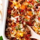Hamburger casserole in a white baking dish with spoon.