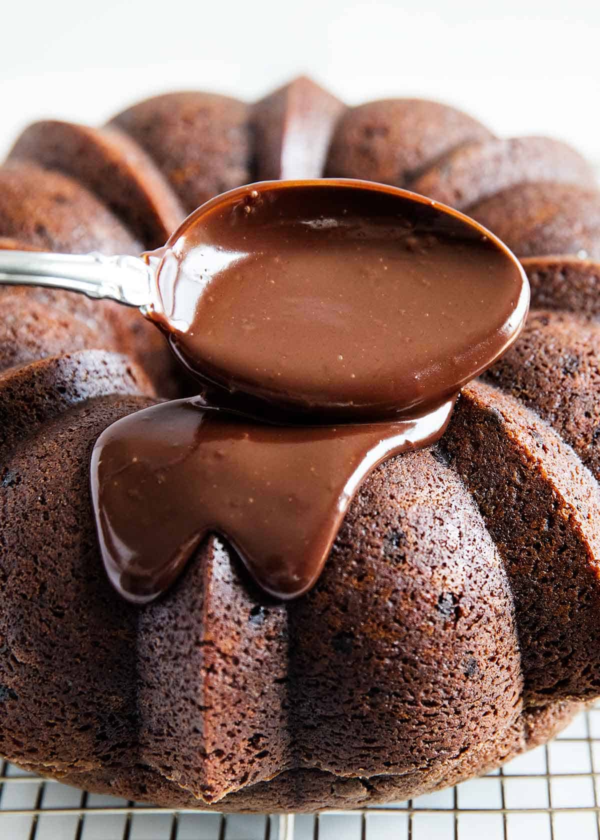 Chocolate ganache being spooned on a chocolate bundt cake. 
