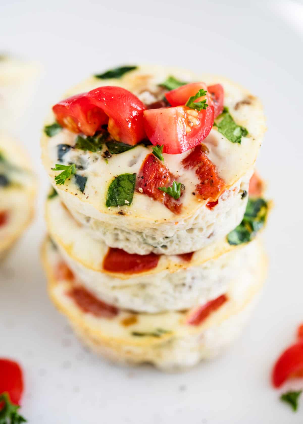 Egg white muffins stacked on top of each other with tomatoes garnished. 