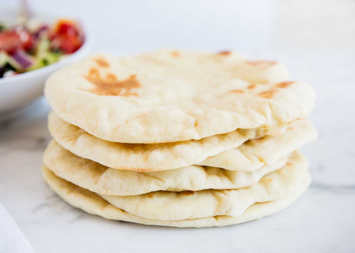 Stacked pita bread on counter with salad.